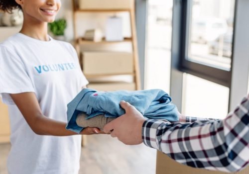 cropped-view-of-african-american-volunteer-giving-clothes-to-man-in-charity-center.jpg